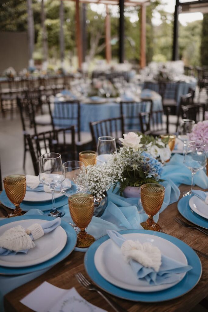 pexels photo 28931889 Beautifully decorated outdoor wedding reception table with blue theme and floral centerpiece.